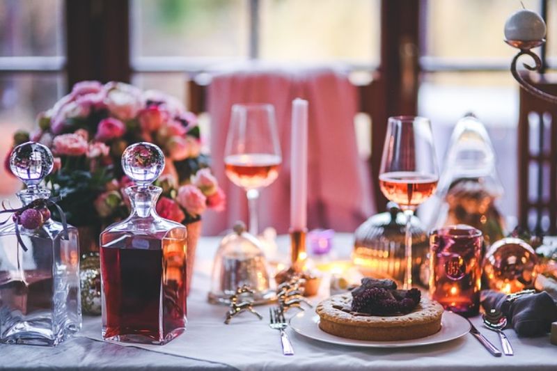 decor de iarna cu o masa festiva, prajitura, pahare cu vin rose
